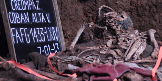 Left side shows a chalkboard reading "CREOMPAZ, Alta Verapaz" and the date, July 1, 2013. Next to the chalkboard are the uncovered human remains in an exhumed pit.
