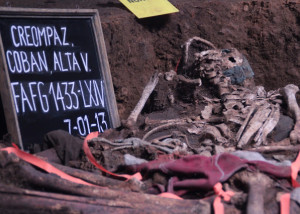 Left side shows a chalkboard reading "CREOMPAZ, Alta Verapaz" and the date, July 1, 2013. Next to the chalkboard are the uncovered human remains in an exhumed pit.