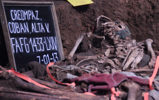 Left side shows a chalkboard reading "CREOMPAZ, Alta Verapaz" and the date, July 1, 2013. Next to the chalkboard are the uncovered human remains in an exhumed pit.