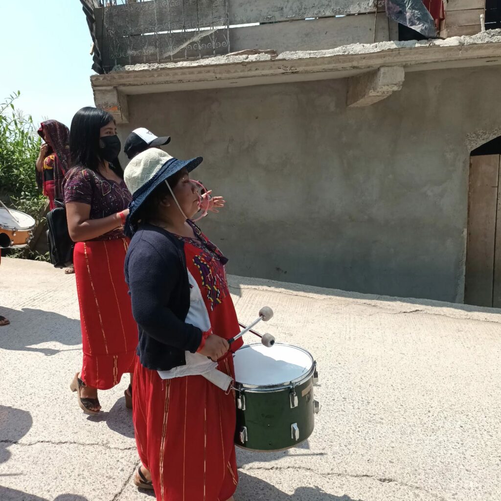 Se ven tres mujeres vestidas de rojo, con tambores caminando // three women dressed in red, with drums walking