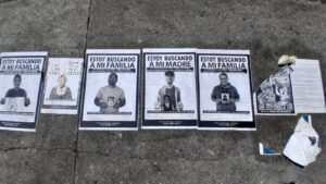 [ENG] Black and white photography wheatpasted on the cement floor of the Central Plaza of Guatemala, of adults holding their photograph as children. Written on the upper part of the poster: "I am looking for my family."
