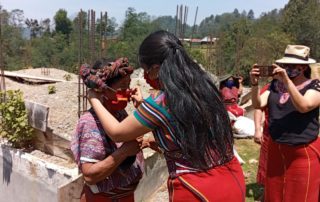 Una representante de la AJR le ayuda a pobladora a ponerse mascarilla. Foto: AJR