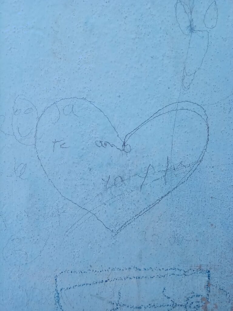 ESP: En una pared blanca dibujado con lápiz un corazón, al centro dice: Te amo. ENG: On a white wall drawn with pencil a heart, in the center it says: I love you.
