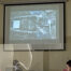 The photo above the court screen shows a photo of one of the graves where a skeleton can be seen. Below is the judge looking at the photo and on the left is the face of a man sitting in the row of lawyers. ////en foto se observa arriba la pantalla del tribunal se observa una foto de uno de las fosas donde se puede ver una osamenta. Abajo se observa al juez titular mirando la fotografia y se observa en la izquierda el rostro de un hombre sentado en la fila de abogados