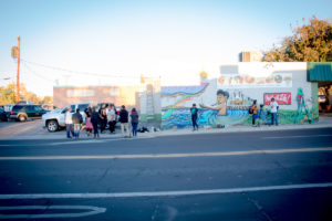 A photograph of people gathering around a mural.