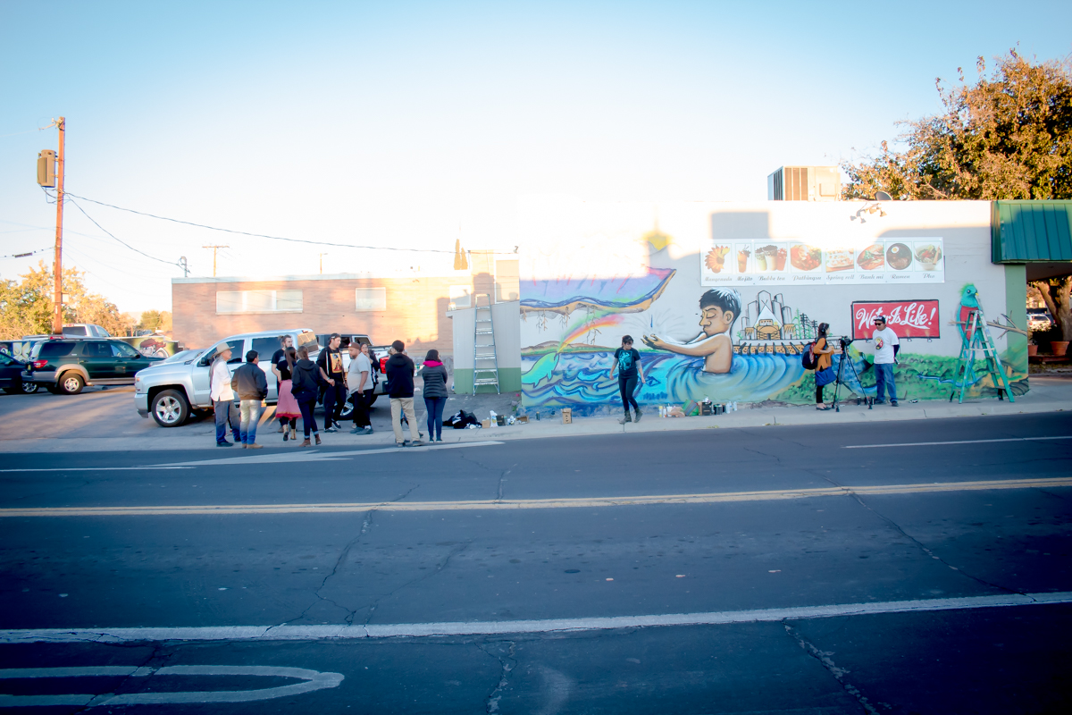 A photograph of people gathering around a mural.
