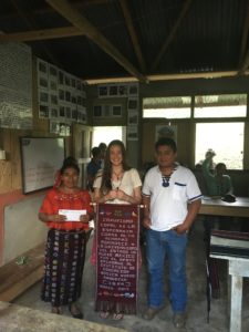 Kayla poses with members of the local Community Development Committee (COCODE), Fabiana and Enrique, holding Copal AA's gift to the delegation.