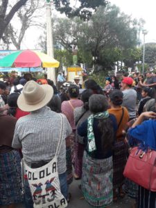 The march against the Amnesty Law in Chimaltenango began at the city's statue for Dignification of the Victims of the Internal Armed Conflict. Pictured: a crowd of people in front of a statue of a Mayan woman tearing apart a gun.