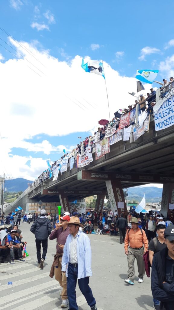In an open street, there is an overpass and many people with banners.