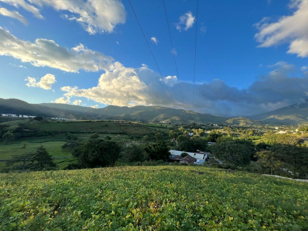Paisaje de Guatemala. Con cielo azul y hierba verde y montañas al fondo.